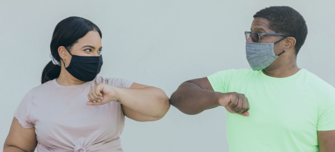 two people bumping elbows with masks on
